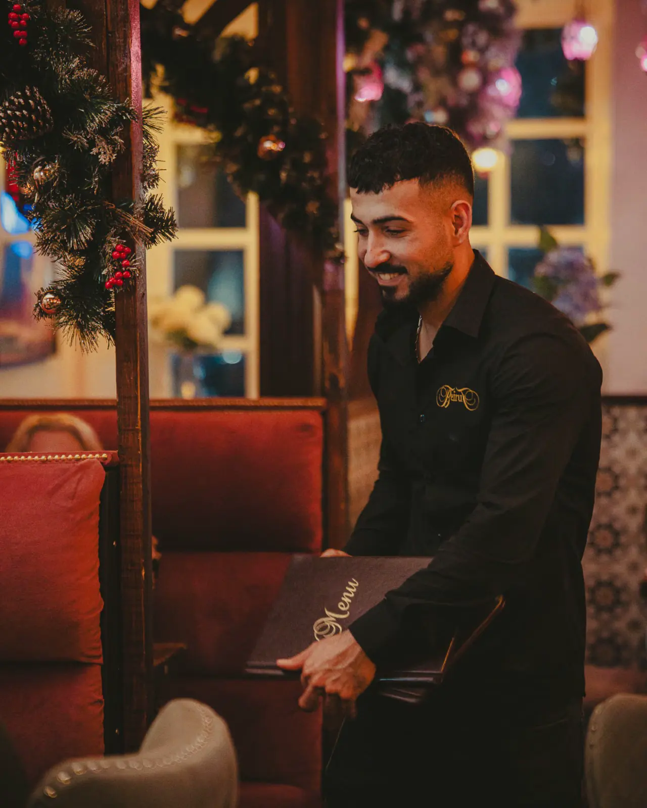 Waiter with the menu by the Christmas garland at Beirut Restaurant, Edinburgh